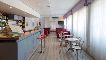 Eine moderne Hotelhalle mit Barbereich, Sitzgelegenheiten und einem Fernseher.