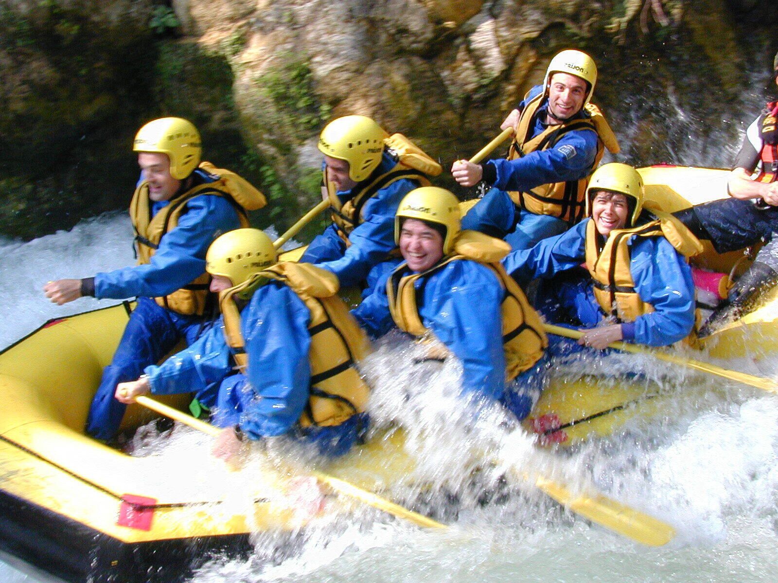 A group of people in a yellow raft navigating a river.