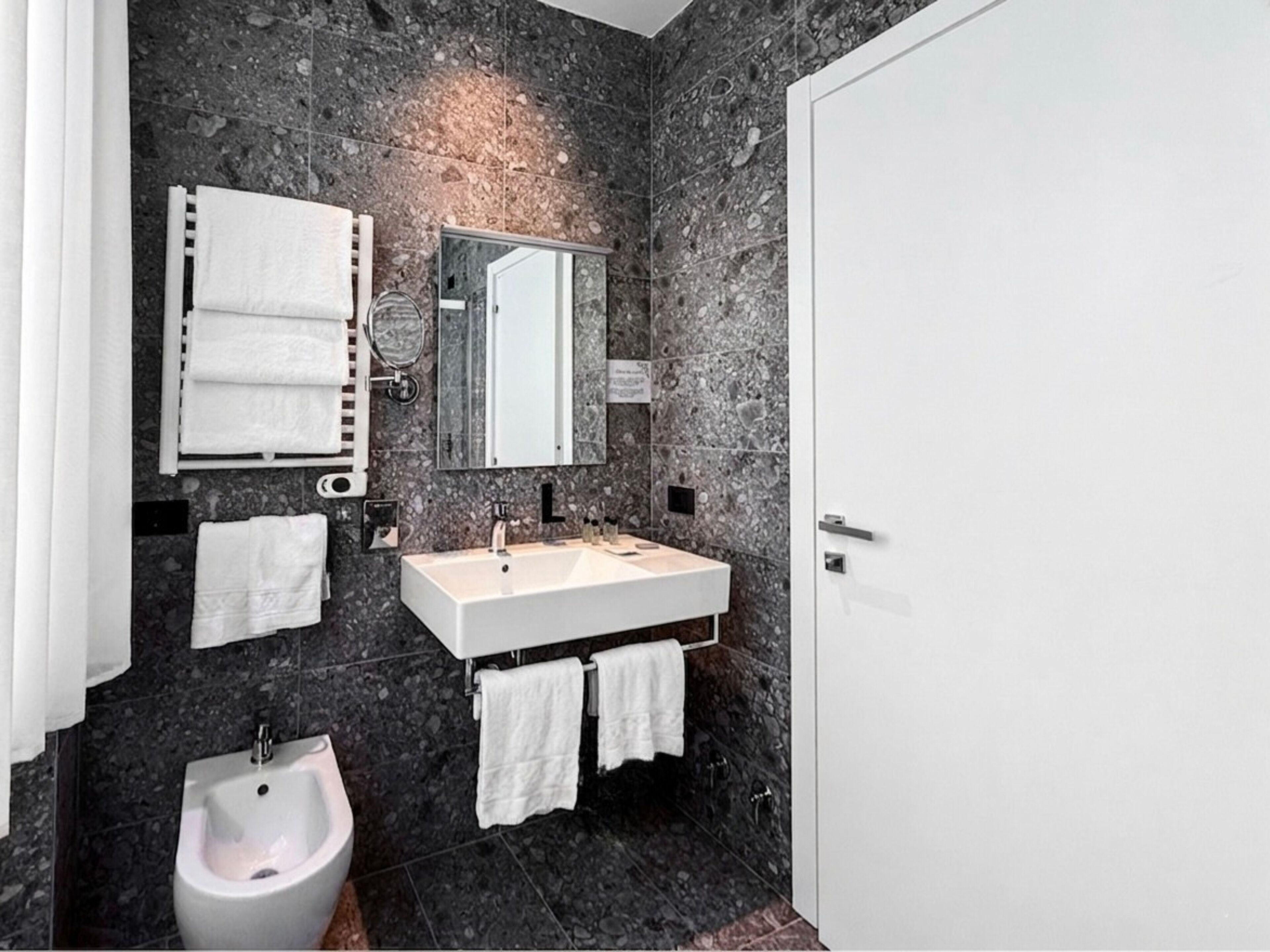 Un bagno con lavandino bianco, un bidet, uno specchio e asciugamani.