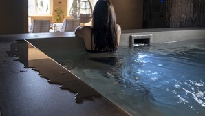 A person in a bathtub with a view of a dining area and a wall with a textured pattern. - Hotel Del Lago 1934 & SPA (Terni)