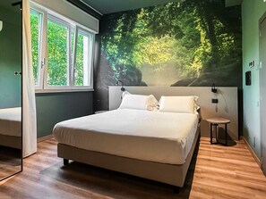 A bedroom with a large bed, a small bedside table, a wall-mounted lamp, and a window with curtains. - Hotel Del Lago 1934 & SPA (Terni)
