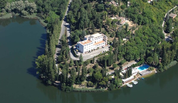 An aerial view of a lakeside property with a large building, a swimming pool, and docked boats. - Hotel Del Lago 1934 & SPA (Terni)