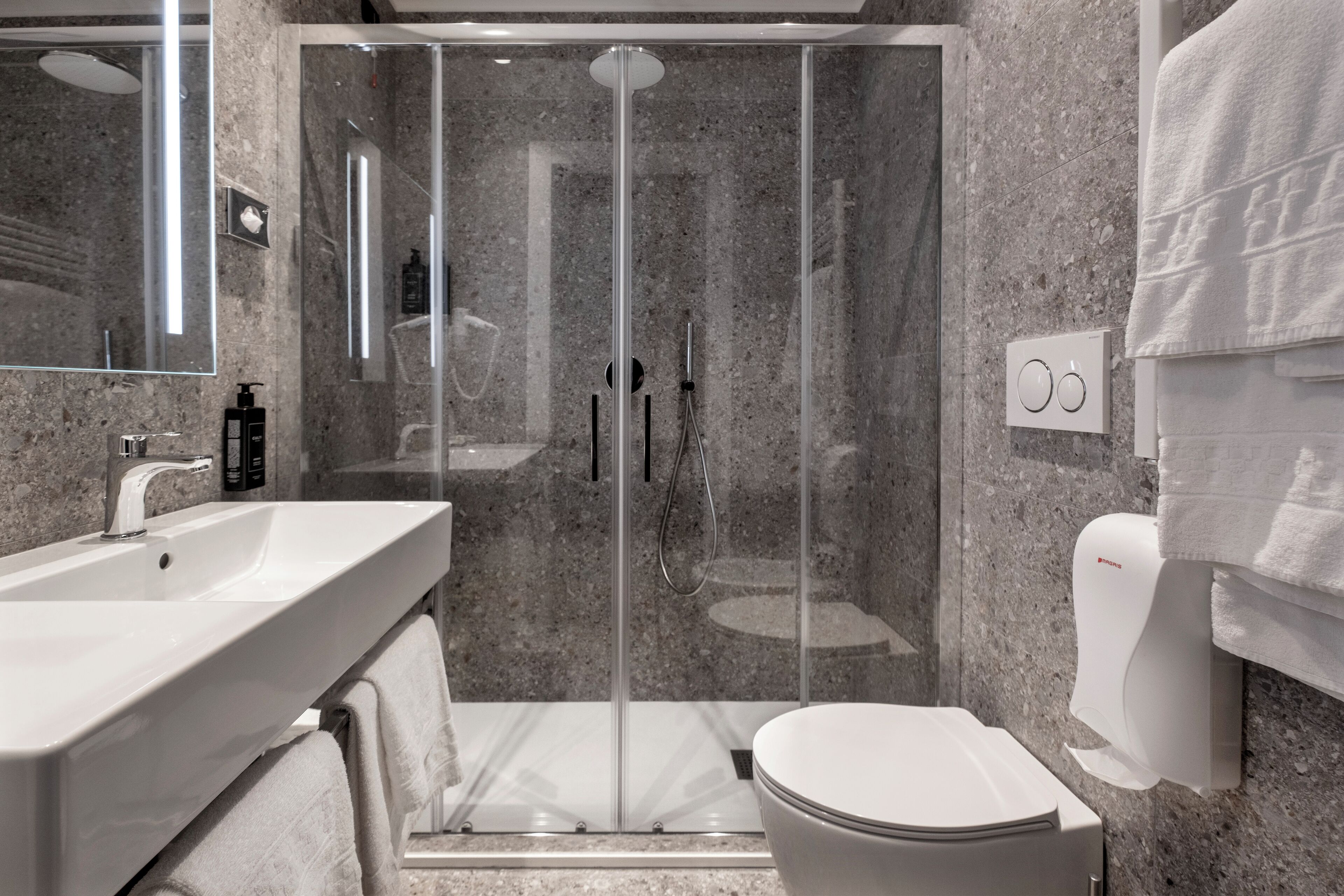 Une salle de bain moderne avec une douche à parois de verre, un lavabo blanc et des toilettes.