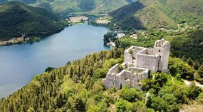 A historic castle surrounded by lush greenery and a lake. - Hotel Del Lago 1934 & SPA (Terni)