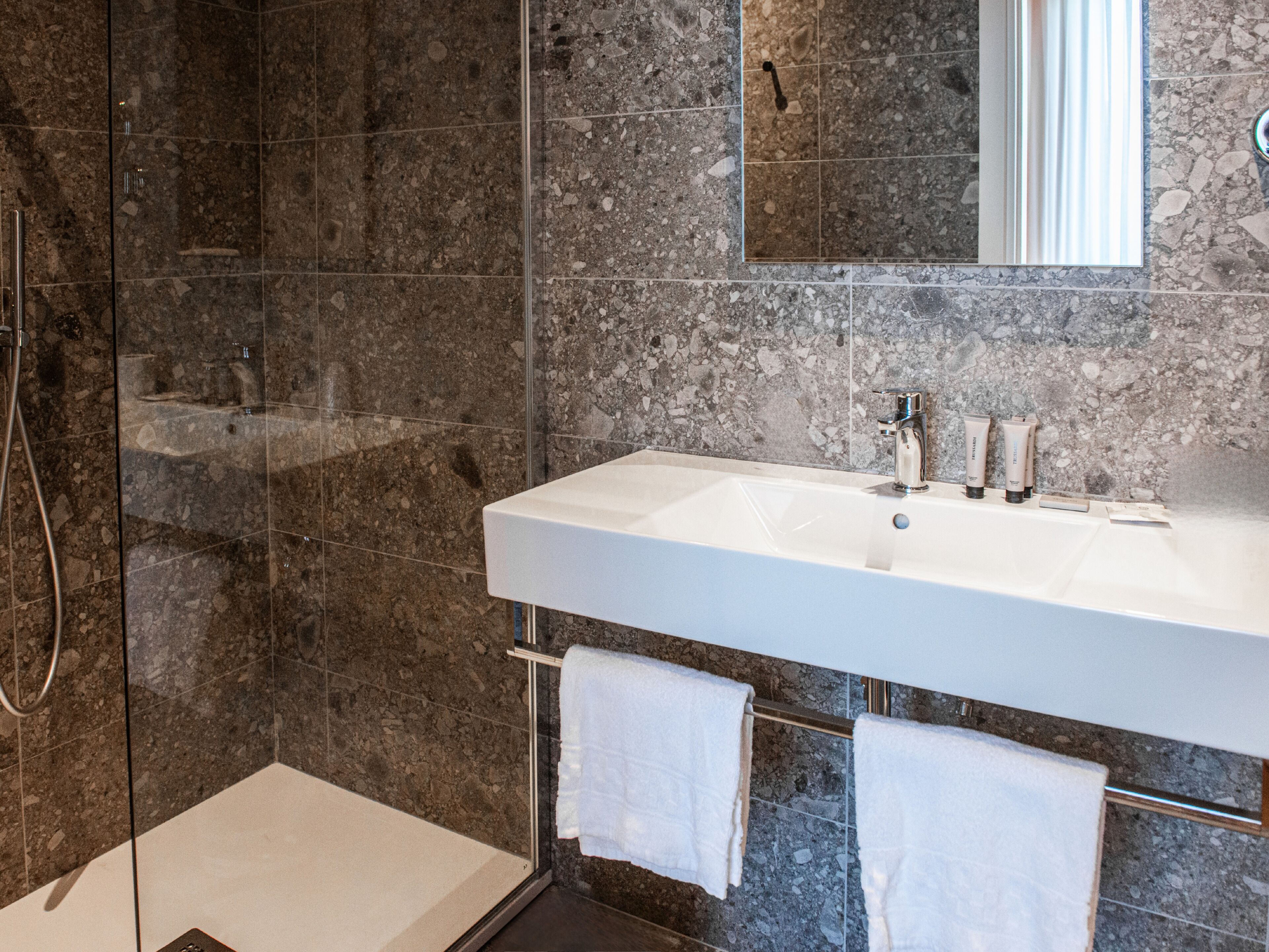Een moderne badkamer met een wit wastafelmeubel, een spiegel en een douchehoek.