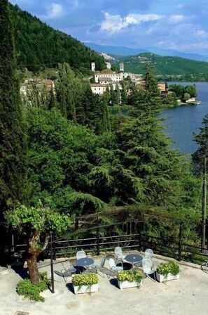 A terrace with outdoor seating and a view of a lake and mountains. - Hotel Del Lago 1934 & SPA (Terni)
