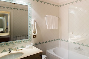 A bathroom with a sink, mirror, towel rack, and bathtub.