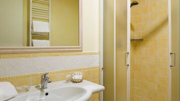 A bathroom with a sink, mirror, and shower.