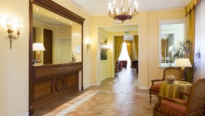 A hotel lobby with a grand mirror, a chandelier, and a reception desk. - Tuder (Todi)