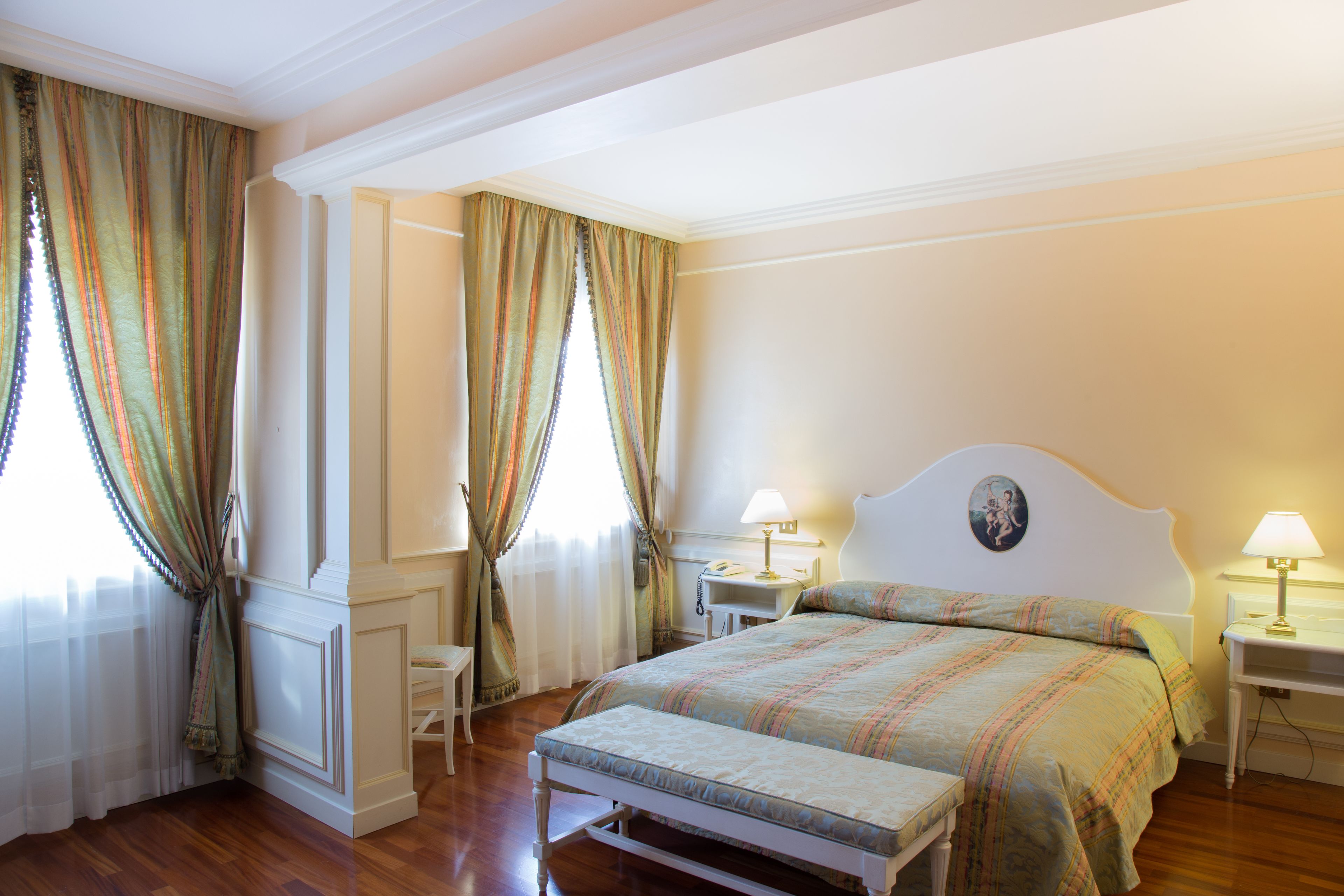 Un dormitorio con cama, mesitas de noche, una silla y cortinas.