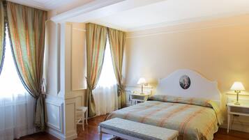 Un dormitorio con cama, mesitas de noche, una silla y cortinas.