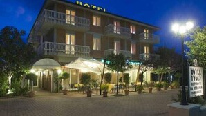 A hotel with a balcony on the second floor, a covered outdoor seating area, and a sign indicating a restaurant. - Tuder (Todi)