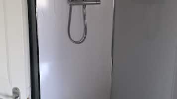 A shower enclosure with a handheld showerhead, a rain showerhead, and a handheld shower attachment.