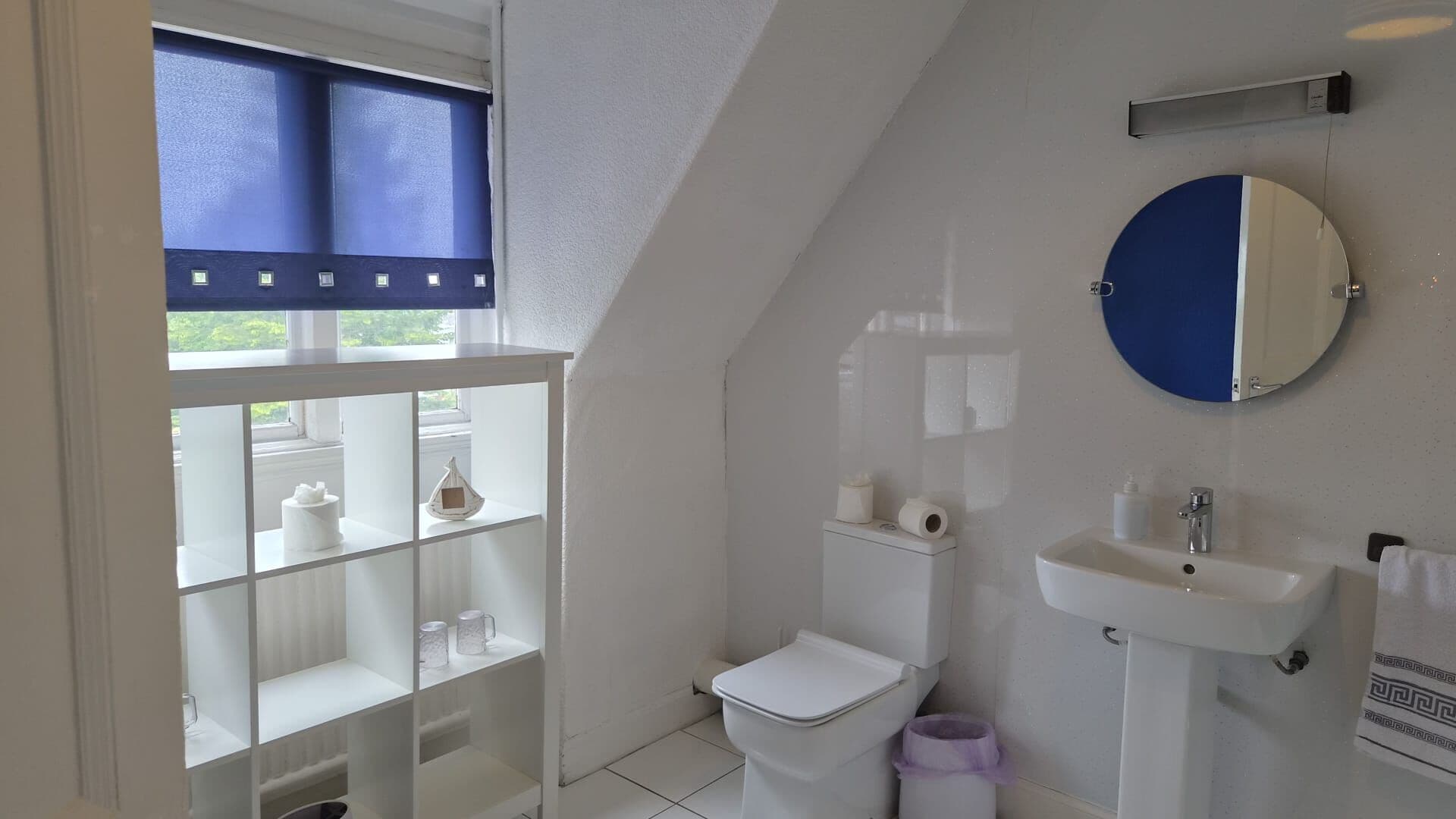 Un bagno con il water, un lavandino e uno scaffale con articoli da toilette.