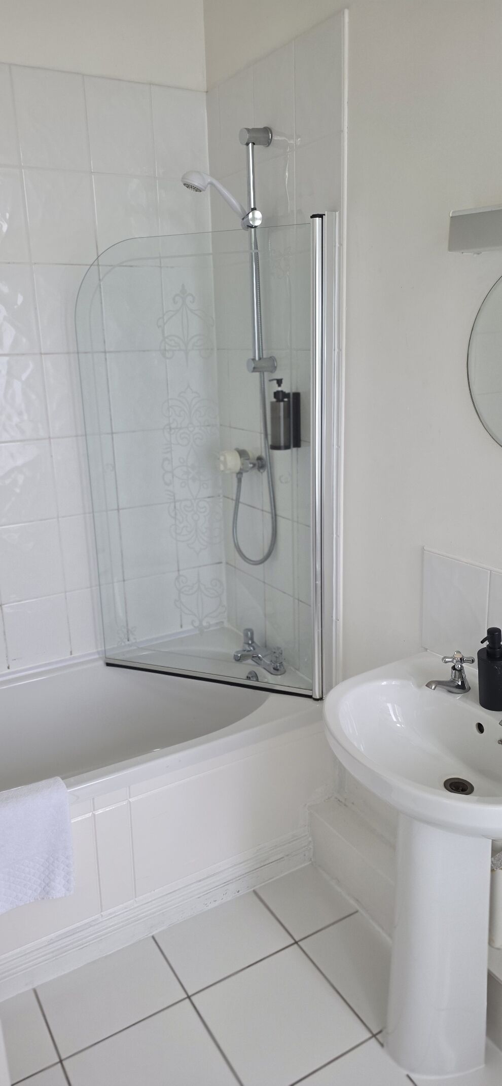 A bathroom with a glass-enclosed shower, a white bathtub, and a pedestal sink.