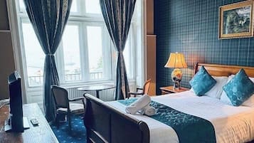 A hotel room with a bed, bedside table, lamp, and a view of the city through the window.