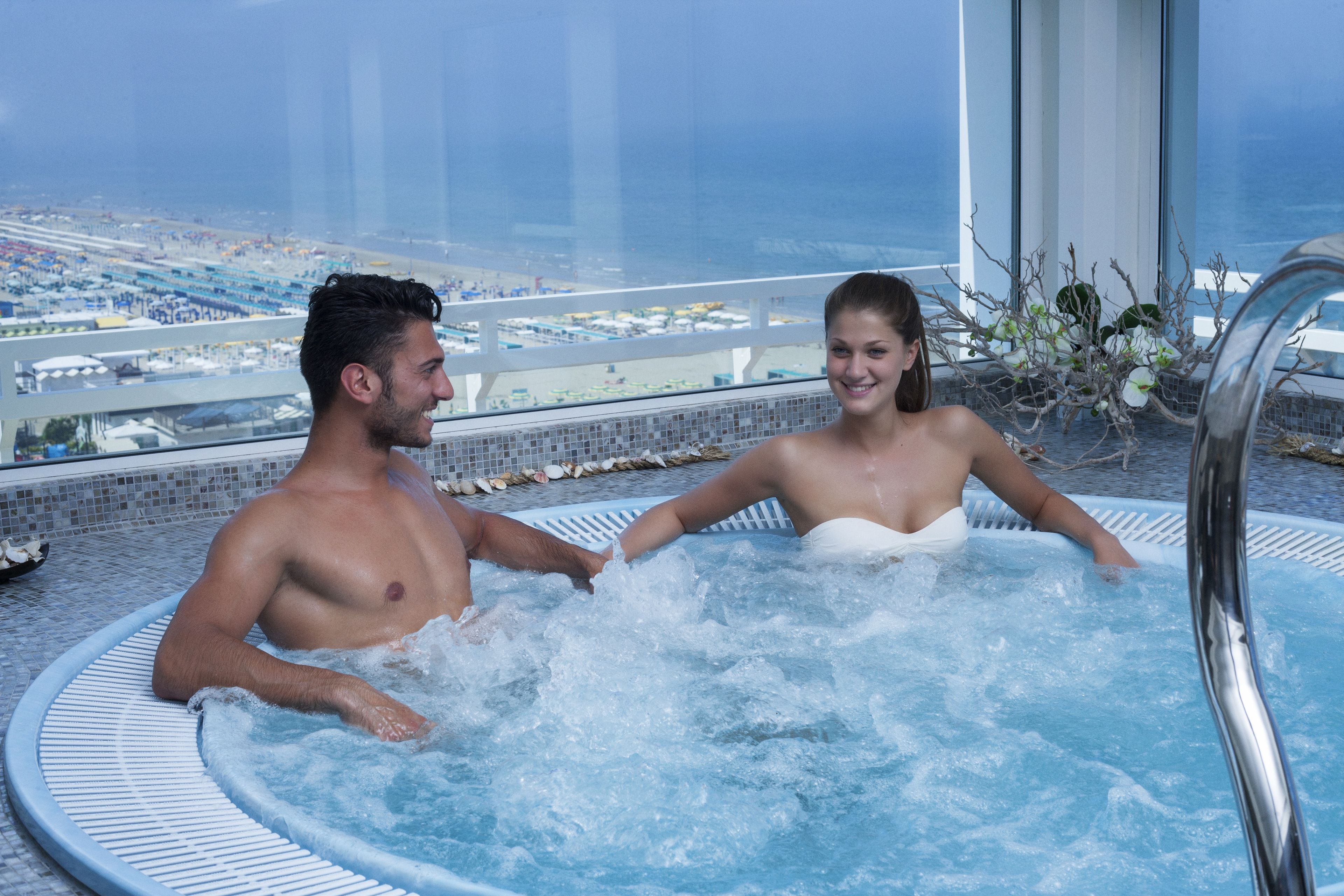 Una pareja en un jacuzzi con vistas a la ciudad.