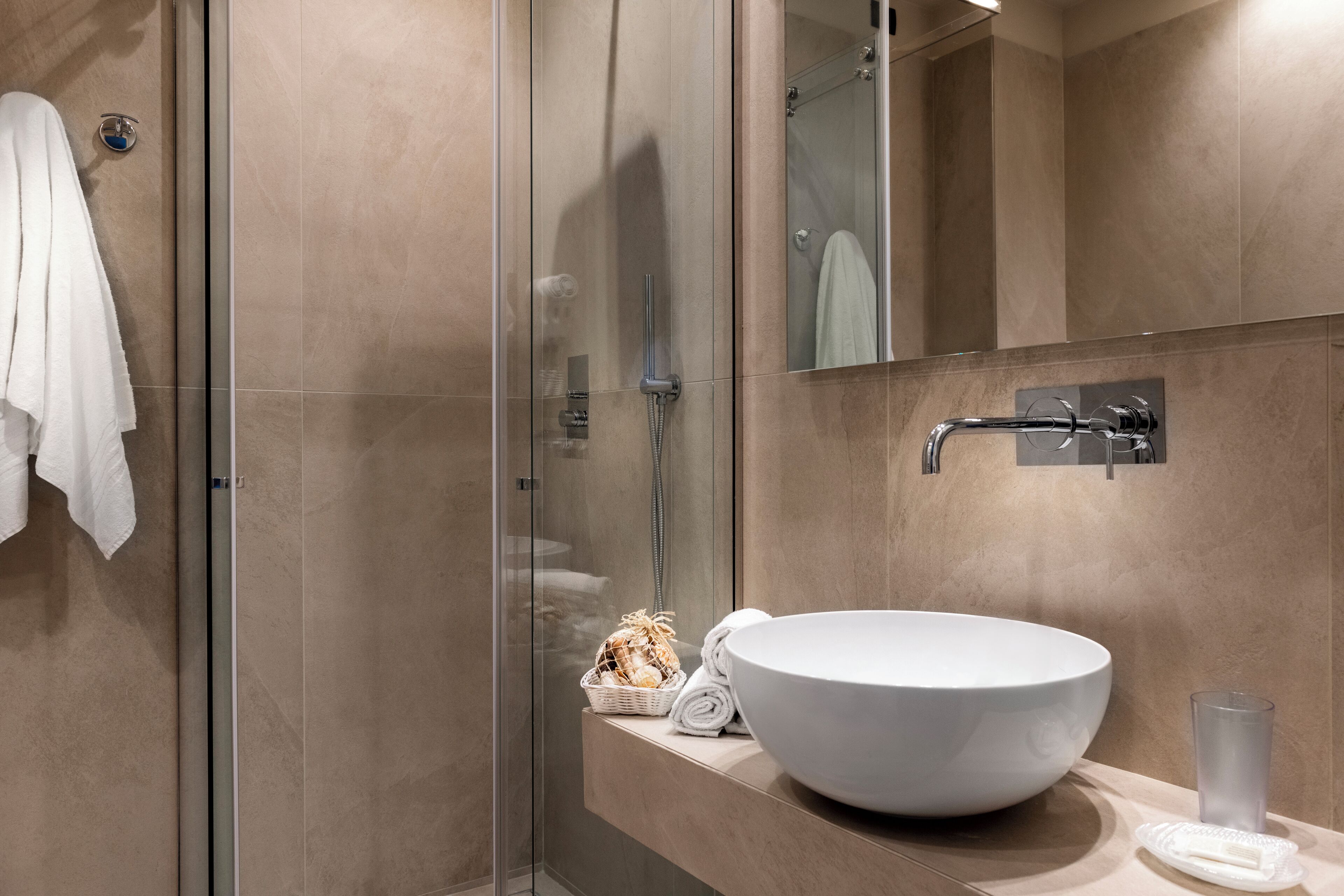 Un bagno moderno con doccia vetrata, un ampio lavandino bianco e un porta asciugamani.