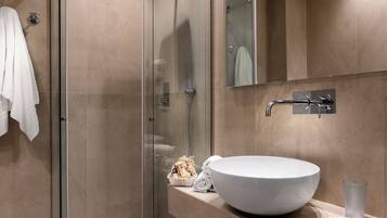 Un bagno moderno con doccia vetrata, un ampio lavandino bianco e un porta asciugamani.