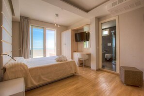 A hotel room with a bed, a desk, a TV, and a shower.