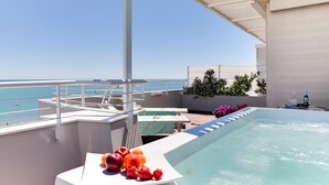 A hot tub with a view of the sea, a table with fruit, and a covered seating area. - Commodore (Riccione)