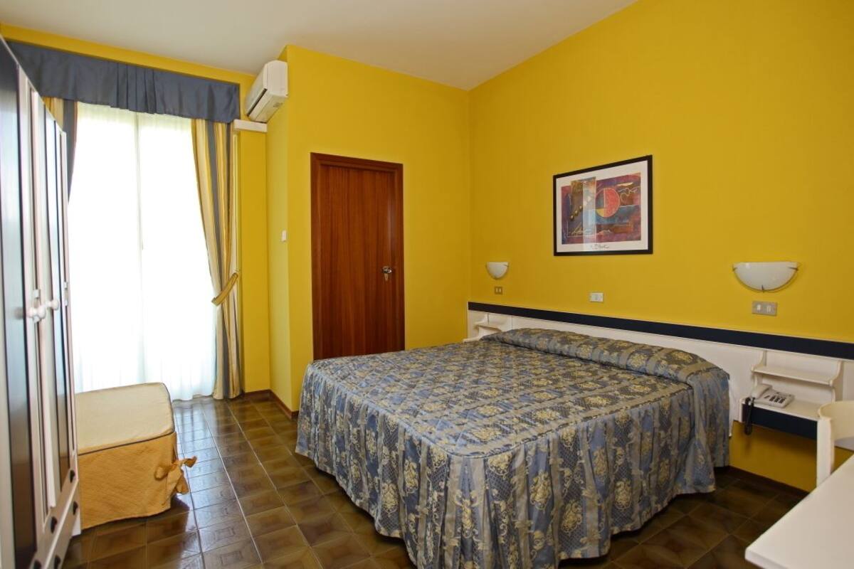 A room with a bed, a chair, a desk, and a door.