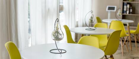 A modern dining area with round white tables and bright yellow chairs.
