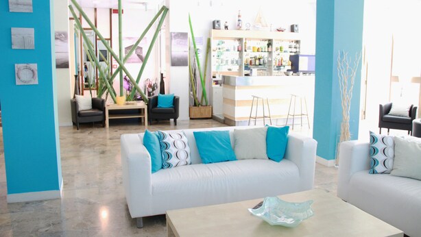 Een moderne woonkamer met een witte bank, een salontafel en een barretje op de achtergrond.