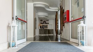 Een hotel lobby met een modern design, met een gebogen plafond, een receptiebalie en een collectie ingekaderde foto's.