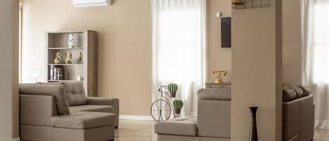 A living room with two sofas, a bookshelf, a bicycle, and a vase.