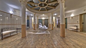 Un hall d’entrée spacieux, doté d’un plafond haut, d’un sol en marbre et de colonnes de style classique.