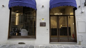 A hotel entrance with a sign reading "COSMOS hotel," large windows with blue awnings, and a visible fire extinguisher. - Hotel Cosmos (Florence)