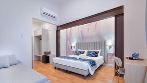 A modern bedroom with a large bed, a bedside table, a chair, and a desk. - Hotel Cosmos (Florence)