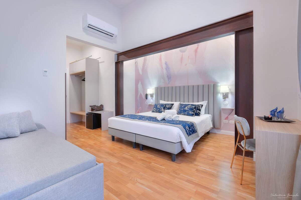 Een moderne slaapkamer met een groot bed, een nachtkastje, een stoel en een bureau.