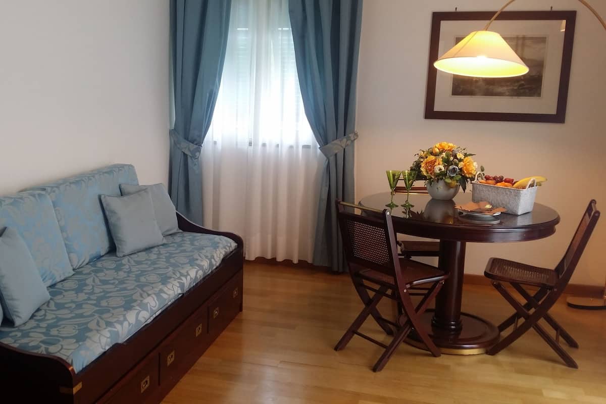 Ein Zimmer mit einer Couch, einem Esstisch mit Stühlen, einer Lampe und einem gerahmten Bild an der Wand.