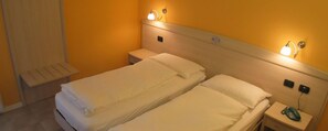 Una cama doble con dos mesitas de noche, cada una con una lámpara y un teléfono.