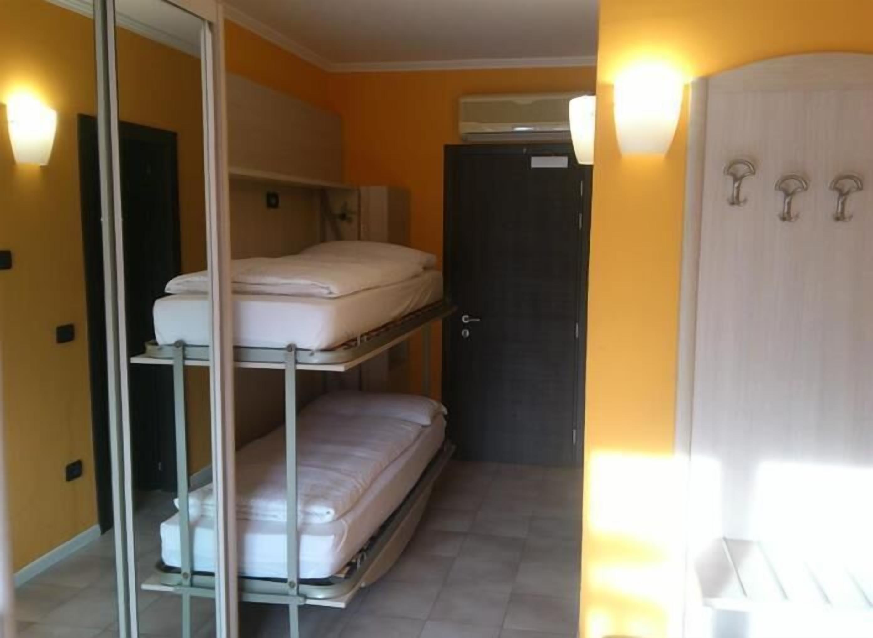 Une chambre d’hôtel compacte équipée de lits superposés, d’une armoire et d’un appareil de climatisation.