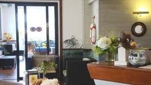 Una zona de recepción con un mostrador de madera, un florero y un reloj en la pared.