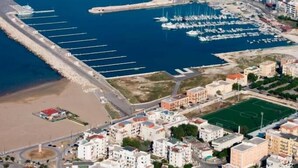 An aerial view of a coastal town with a marina, buildings, and a lighthouse. - Vela Velo Club (Vieste)