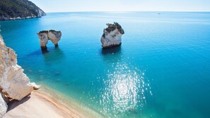 Un paisaje costero con aguas azul turquesa, formaciones rocosas y una playa arenosa.