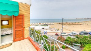 A balcony with a view of a beach, a parking area, and a small garden. - Vela Velo Club (Vieste)