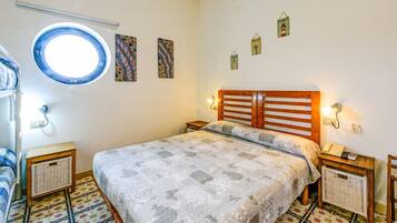 Quarto com cama, um claraboia redonda e uma pequena janela.