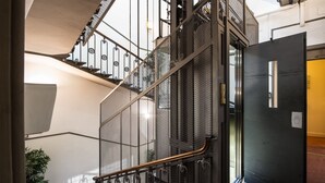 Una escalera con barandillas metálicas y una puerta negra.