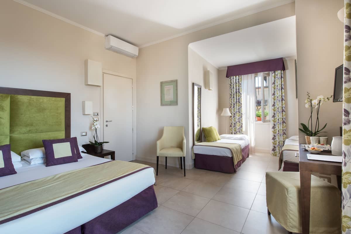 Une chambre d’hôtel avec deux lits, une chaise, un bureau et un téléviseur.