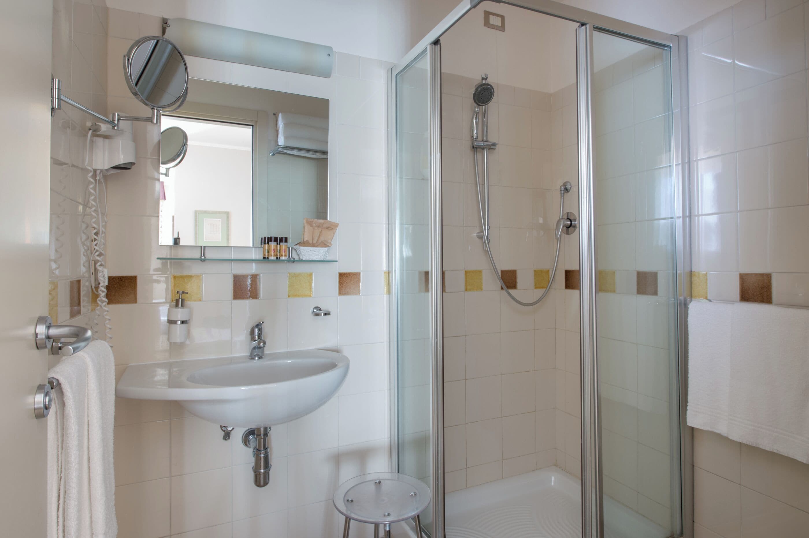 Ein modernes Badezimmer mit Duschabtrennung aus Glas, Waschbecken und Spiegel.