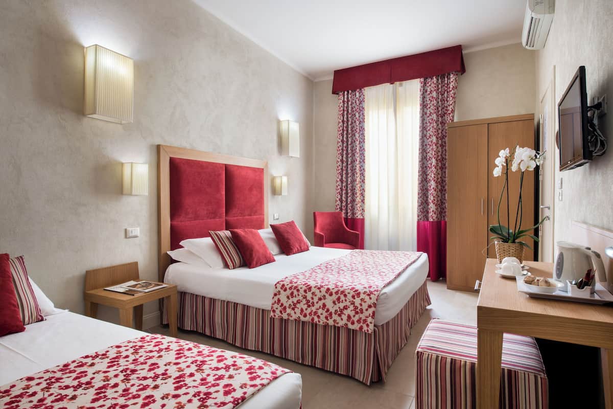 Une chambre d’hôtel avec un grand lit, des tables de chevet, un bureau et une télévision.