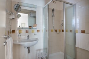 Un bagno con doccia vetro, lavandino e specchio.