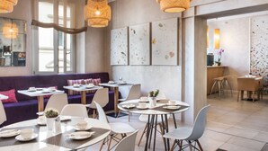 Un café moderno con mesas redondas, sillas blancas y lámparas de mimbre colgantes.