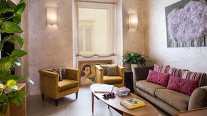 Una sala de estar con un sofá, sillones, una mesa de centro y un cuadro en la pared.