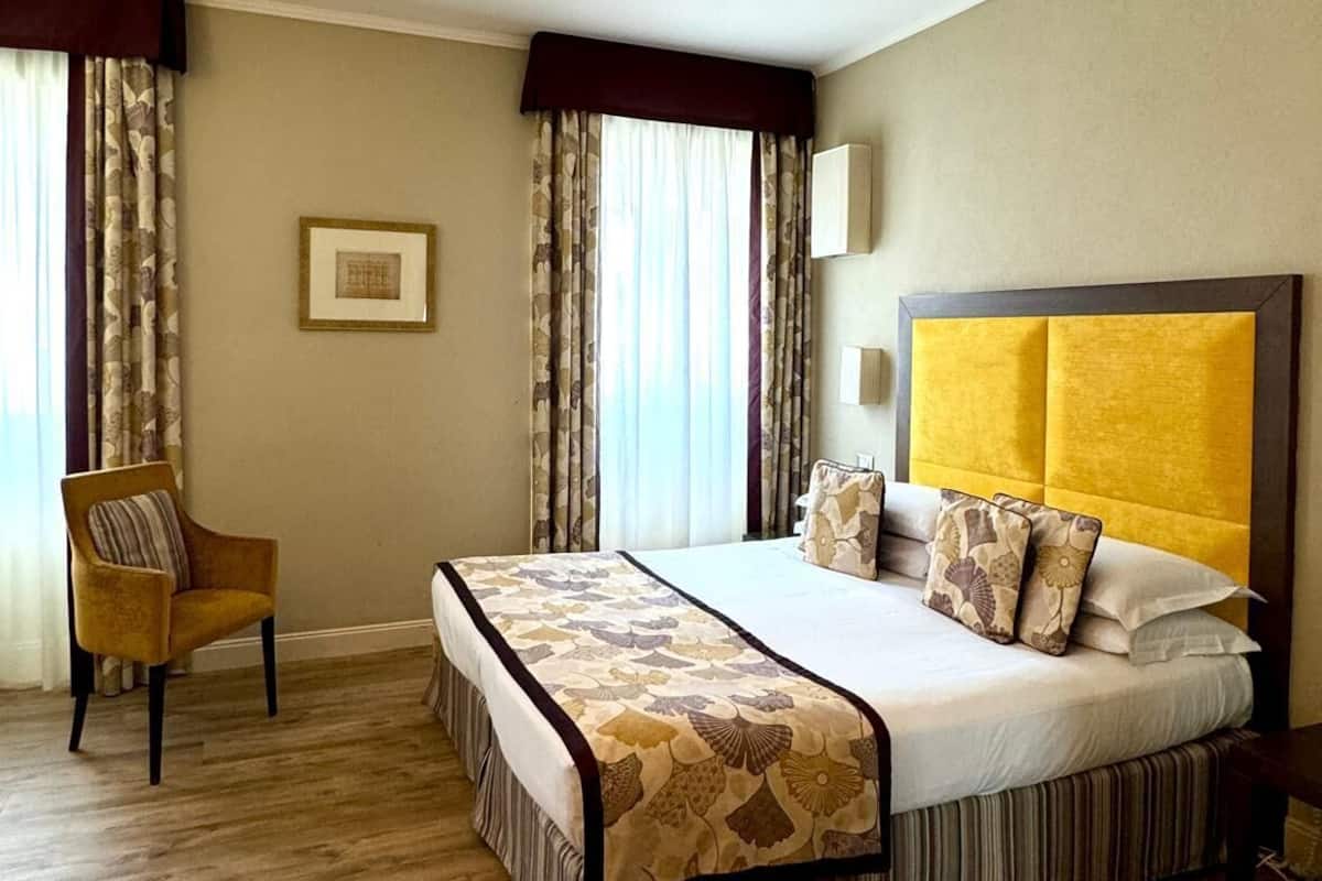 Une chambre d’hôtel avec un grand lit, une chaise et un tableau au mur.